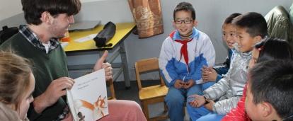 A Projects Abroad volunteer teaching English by reading to the children in China A volunteer reads a book to his students during his teaching work experience in China